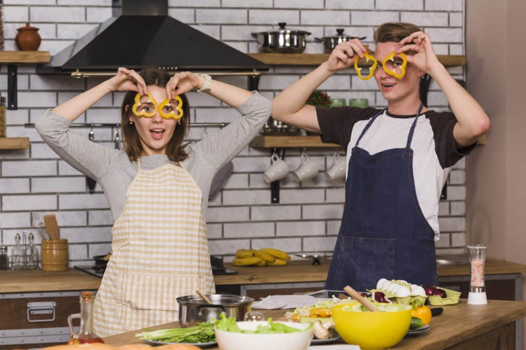 About me 2 Young couple having fun in the kitchen with bell pepper slices over their eyes